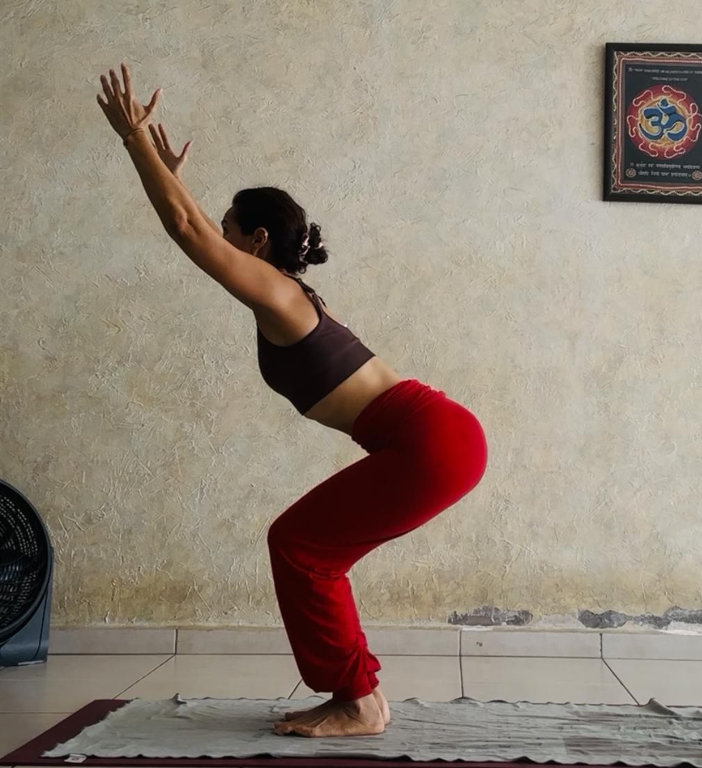 Leticia Mijares en postura de la silla (Utkatasana) con los brazos arriba